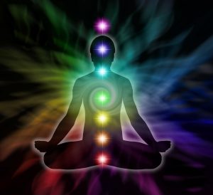 Silouette of a man in lotus meditation position with Seven Chakras on flowing rainbow energy background